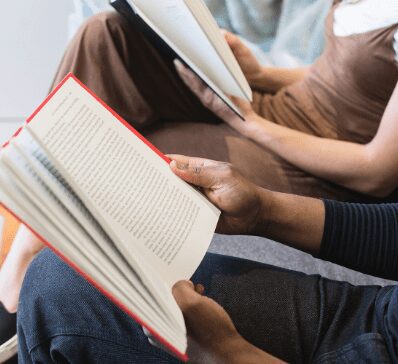 Two people reading books together in a relaxed setting.
