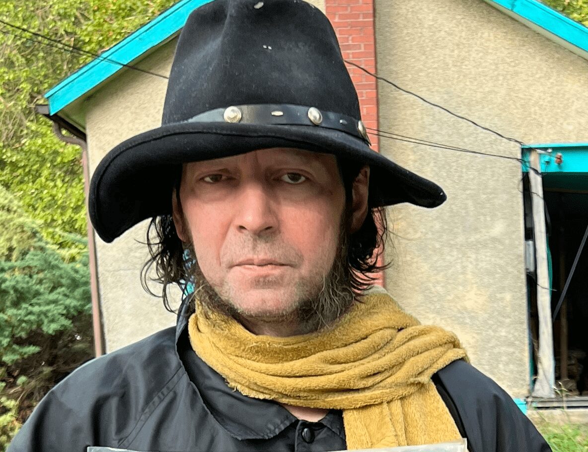 Man wearing a wide-brimmed black hat and a yellow scarf.